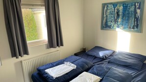 Ein Zimmer mit Bett, Heizkörper, einem fensterbepflegten Fenster und einem Bild an der Wand.