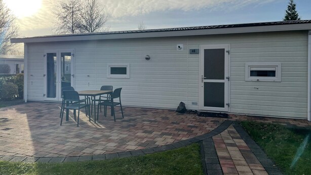 Ein einstöckiges Gebäude mit einer Terrasse, komplett mit Tisch und Stühlen.