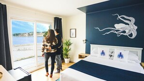 Un dormitorio con una cama grande, vista al mar a través de una puerta corredera y una decoración de pulpo en la pared.