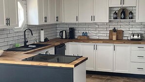 Una cocina moderna con armarios blancos, una isla con encimera negra y un salpicadero de azulejos.