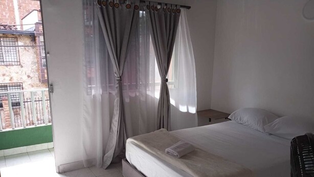 Ein Schlafzimmer mit Bett, Nachttisch und Blick auf ein Backsteingebäude.