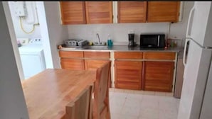 Eine kleine Küche mit Holzausstattung, einer Mikrowelle, einem Spülbecken und einem Kühlschrank.