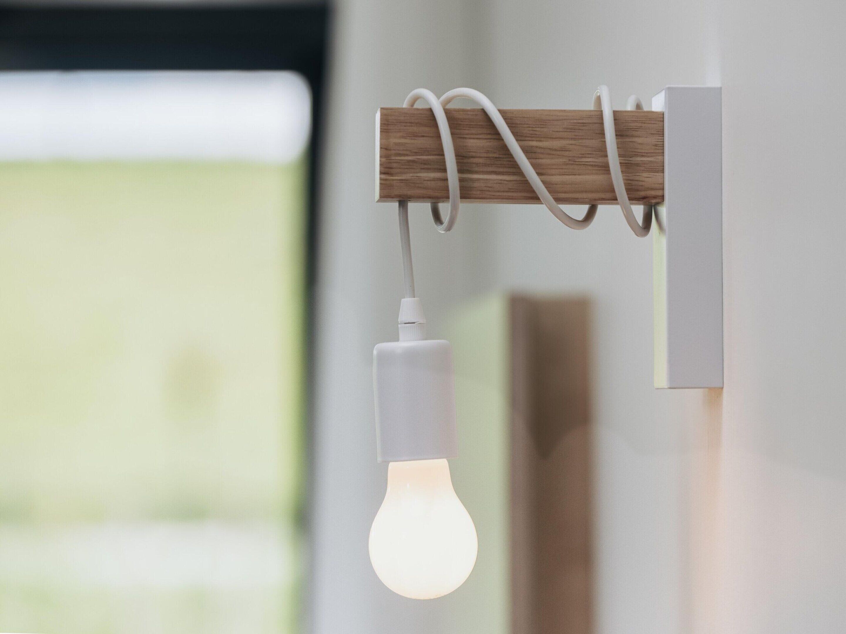 A modern light fixture with a wooden element and a hanging bulb.