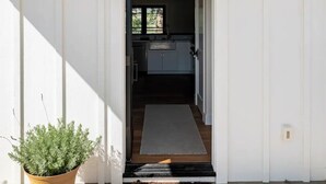 A modern entrance with a concrete floor, a potted plant, and a door leading to a kitchen area.