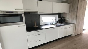 Ett modernt kök med vita skåp, en svart bänkskiva, en inbyggd ugn, ett handfat och en kaffebryggare.