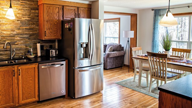 Una cocina moderna con armarios de madera, electrodomésticos de acero inoxidable y un comedor con una mesa y sillas de madera.