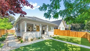 A single-story house with a front porch, a visible garage door, and a well-maintained lawn. - * The Bungalow at Hyde Park * (Boise)