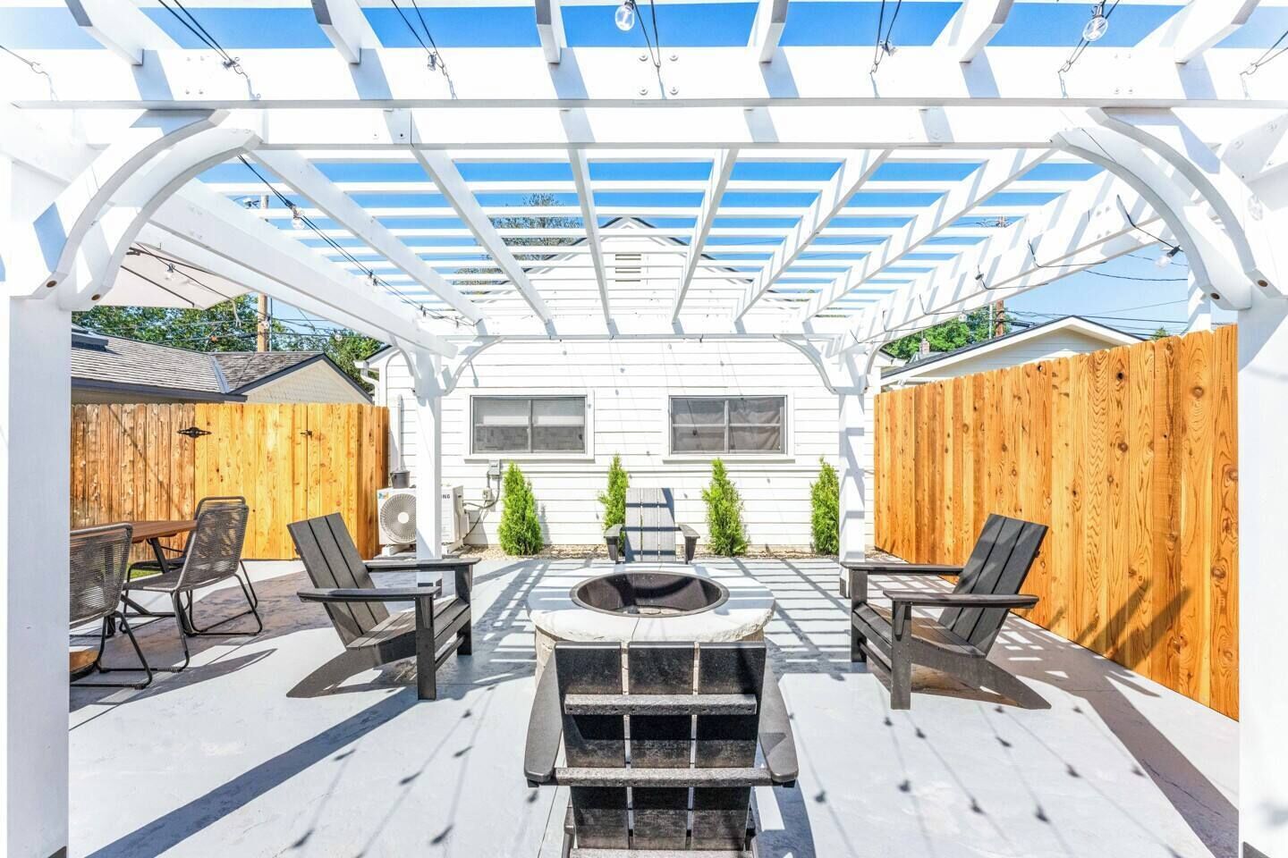 Una veranda coperta con un braciere, posti a sedere all'aperto e una struttura a pergola.