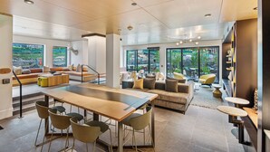 A spacious living area with a large dining table, multiple seating options, and large windows offering views of the outdoors.