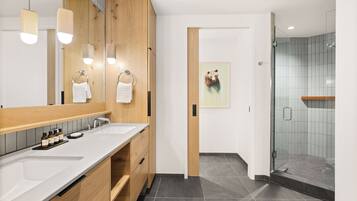 A modern bathroom with a wooden vanity, a large mirror, and a glass shower enclosure.