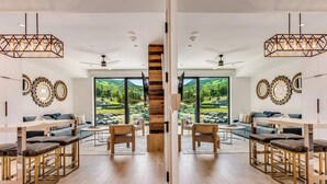 A modern interior with a central staircase, wooden flooring, and large windows offering a view of a green landscape.