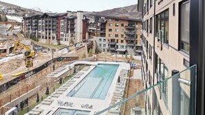 A modern hotel with a pool, multiple floors, and a view of the mountains.