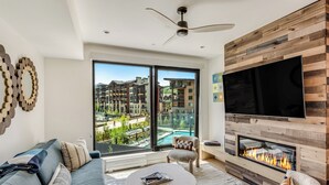 A modern living room with a sofa, coffee table, fireplace, and a large TV.