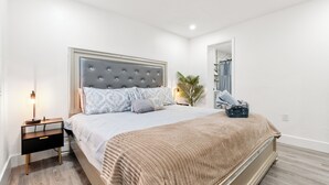 Une chambre à coucher avec un lit, une table de chevet, une lampe et une plante en pot.