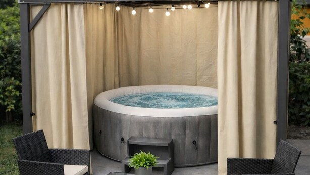 Un bain à remous surmonté d’une pergola, entouré de meubles en osier et d’une table en verre.
