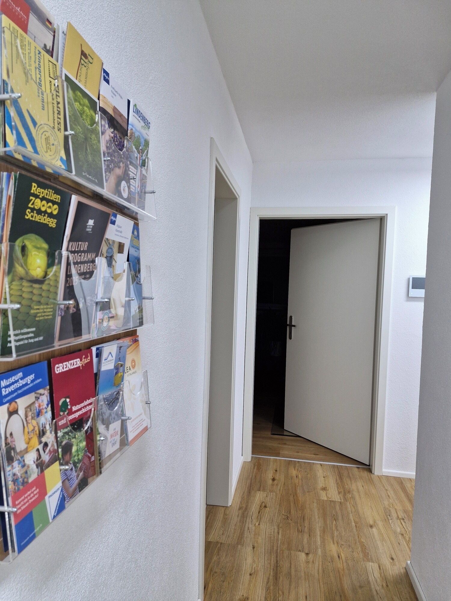 Ein Flur mit Holzboden und einer an der Wand befestigten Broschürenausstellung.