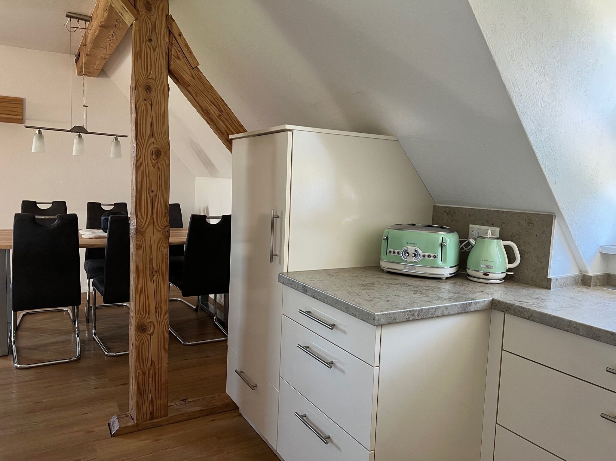 Een compacte keuken met een witte kast, een groene toaster en een waterkoker op het aanrecht.