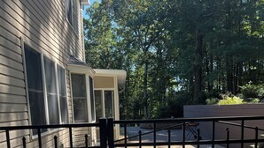 A gated backyard with a house, a paved driveway, and a wooden deck.