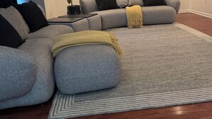 A modern living room with a sectional sofa, a small side table with a plant, and a decorative throw blanket.