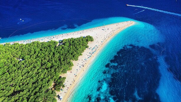 An aerial view of a beach with clear turquoise waters, a sandy shore, and dense green foliage on the left. - Villa Julia with a private heated pool, ideal for large groups (Milna)
