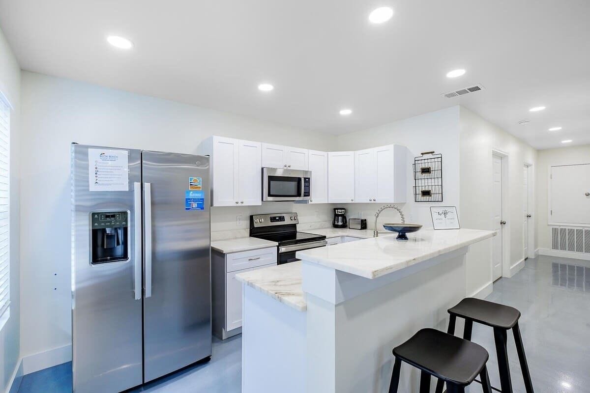 A modern kitchen with stainless steel appliances, white cabinetry, a built-in microwave, and a water dispenser.