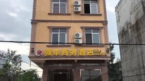 A multi-story building with a yellow facade and multiple windows, some of which have air conditioning units installed.