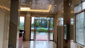 A hotel lobby with a marble floor, a reception desk, and a glass door leading outside.