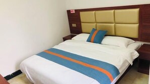 A hotel room with a bed, a wooden headboard, and a nightstand.