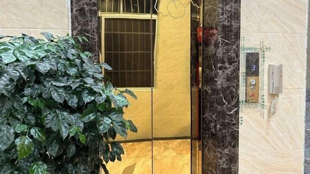 A golden elevator door with a window, a telephone, and a number 3 panel.