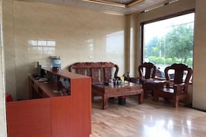 A room with a wooden coffee table, a sofa, and a desk with a computer. - Dongxing Qianghua Business Hotel (Dongxing)