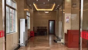 A hallway with a polished floor, a red bench, and a glass door on the right.