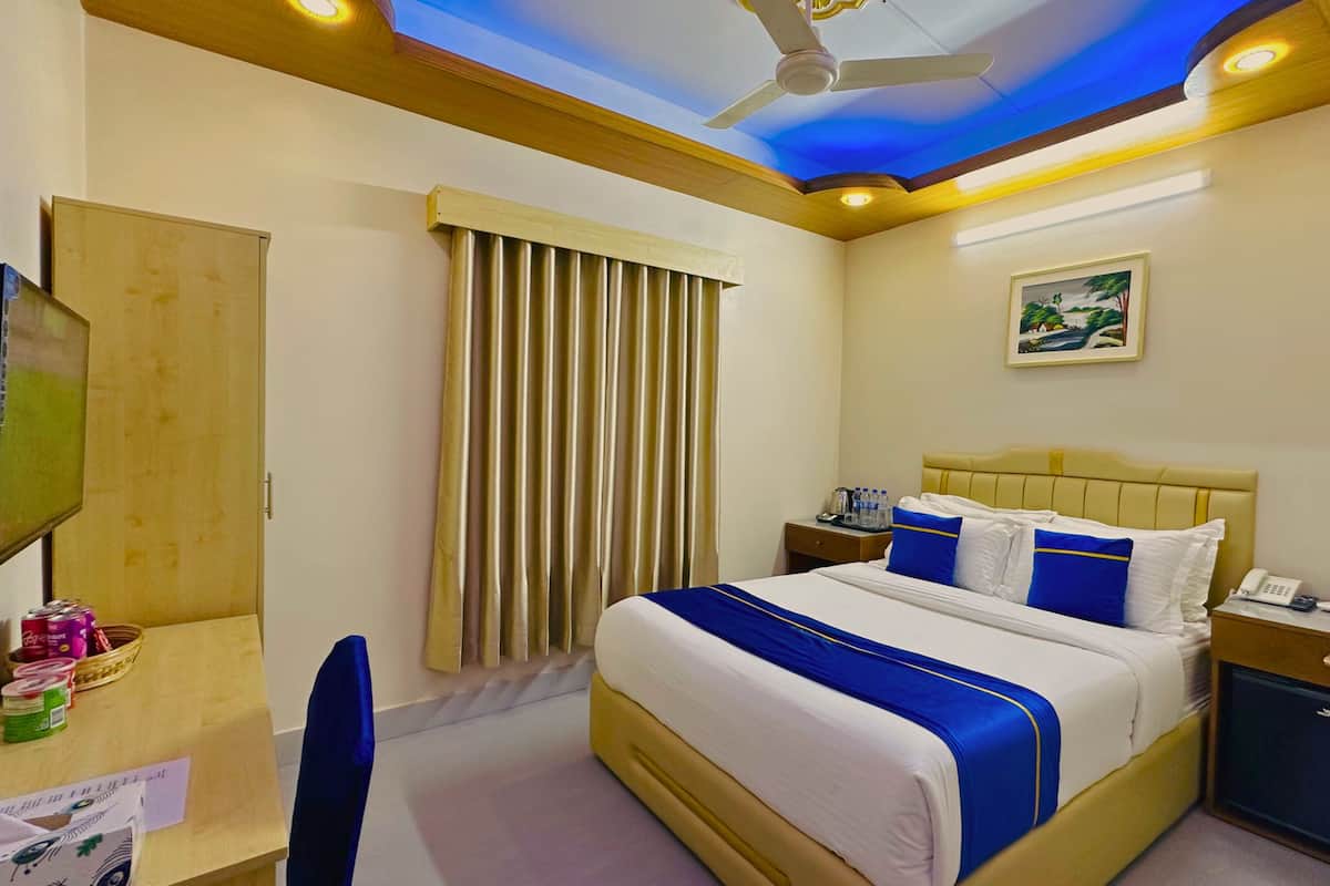 Una habitación de hotel con cama, mesita de noche, televisor y ventilador de techo.