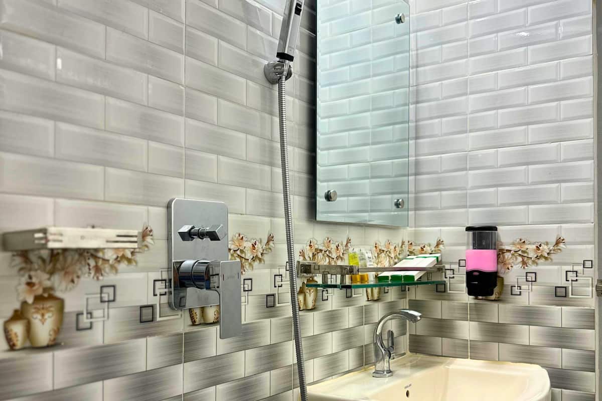 Un baño con ducha, lavabo y espejo.