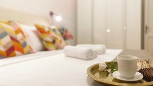 A neatly made bed with colorful pillows, a white cup on a tray, and rolled towels. - Comfortable apartment between Villa Borghese, Trinità dei Monti and Trevi Fountain (Roma)