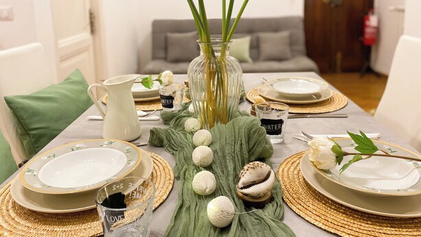 A dining table set with plates, cutlery, and a vase with flowers. - Comfortable apartment between Villa Borghese, Trinità dei Monti and Trevi Fountain (Roma)