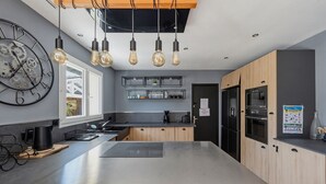 Una cocina moderna con una isla central, iluminación colgante y electrodomésticos integrados.