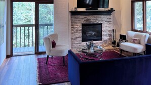 Un salon spacieux doté d’une cheminée, d’un grand téléviseur à écran plat et d’un coin salon confortable.