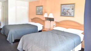 A hotel room with two beds, a nightstand, a lamp, and two framed pictures on the wall. - Arlington inn (Arlington)