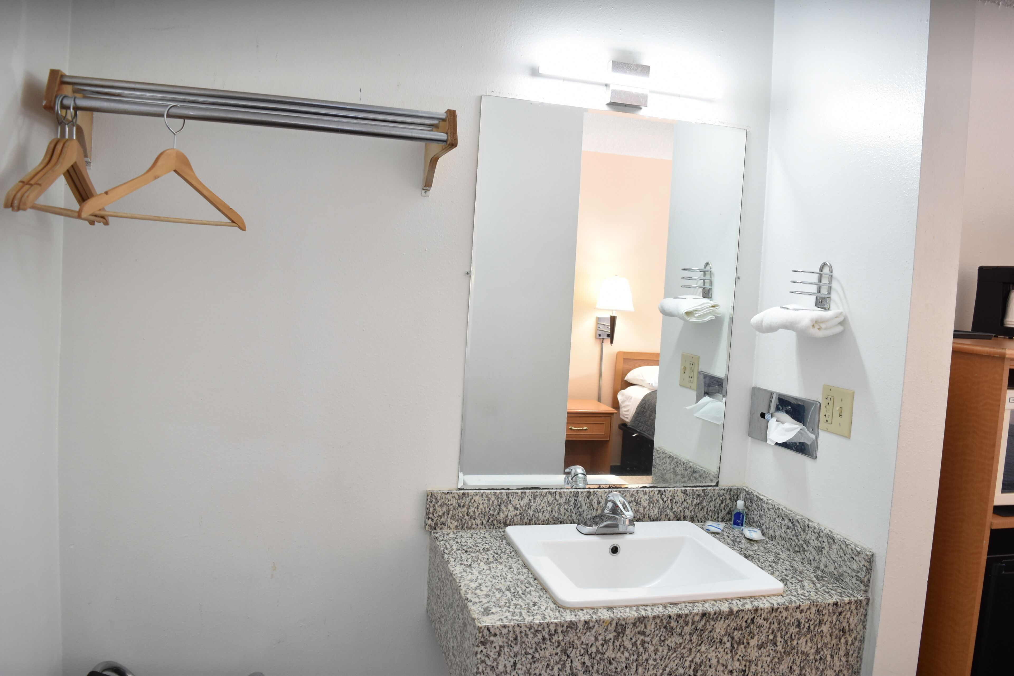 Une salle de bain avec un lavabo doté d’un plan de travail en granit, un miroir, un porte-serviettes et un distributeur de serviettes.