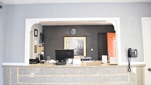 A reception desk with a computer, telephone, and framed picture on the wall. - Arlington inn (Arlington)