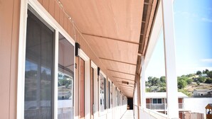 A corridor with an exit sign, large windows, and a view of a hillside. - Arlington inn (Arlington)