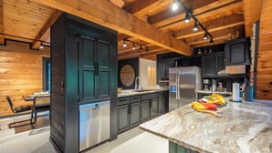 A modern kitchen with wooden beams, a central island, and stainless steel appliances.