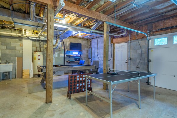 A spacious room with a ping pong table, a pool table, and a brick wall.