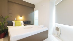 A hotel room with a bed, a bedside table, a potted plant, a wall-mounted TV, and a window. - UrbanViewSanAntonio'sPlaceSampalocManila (Manila)