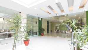 A modern hotel lobby with glass walls, potted plants, and a clock on the wall. - UrbanViewSanAntonio'sPlaceSampalocManila (Manila)