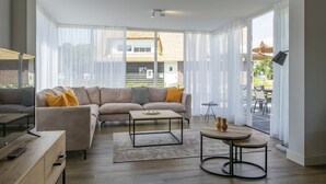 Una sala de estar moderna con un sofá modular, una mesa de centro y una mesa de comedor.