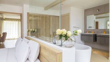 Un baño moderno con un espejo grande, una bañera blanca y un tocador de madera.