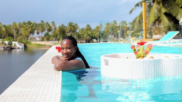 Zona de piscina con una tumbona y una planta decorativa.