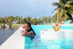 A poolside area with a lounge chair and a decorative plant. - Palms Resort Assinie Managed by Accor (Assouindé)