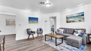 A modern living room with a grey sofa, two armchairs, a coffee table, and a rug. - Tranquil Waterside Retreat (Oakland Park)